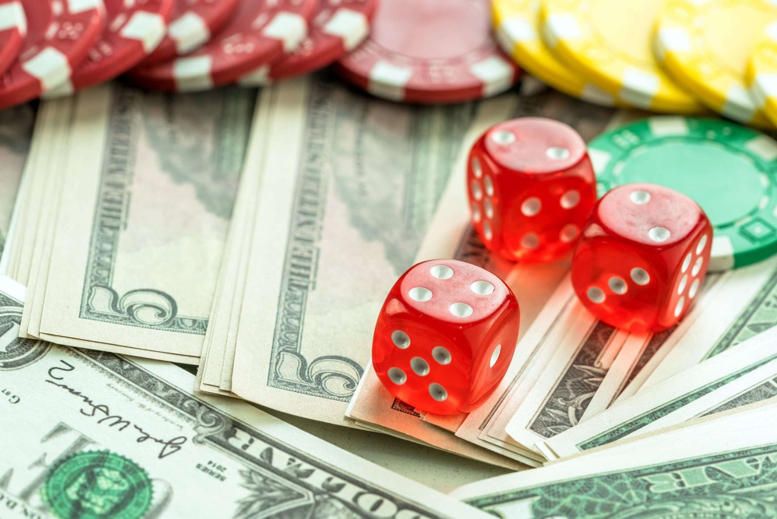 tres dados rojos sobre dolares y fichas de poker
