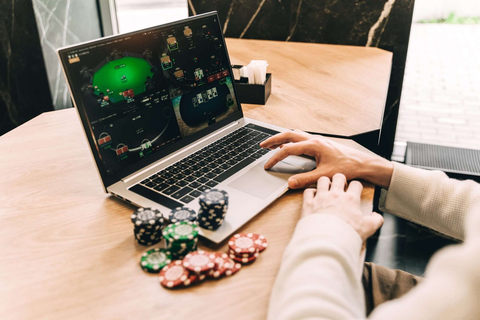 laptop jugando poker online junto a fichas de poker
